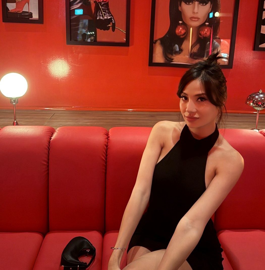 Janina in a black halter dress on a red leather banquette